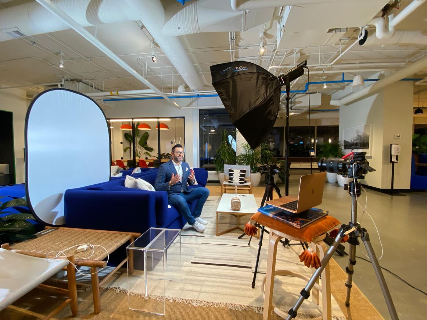 Tom on a blue couch in front of a softbox, mid-conversation during a video shoot